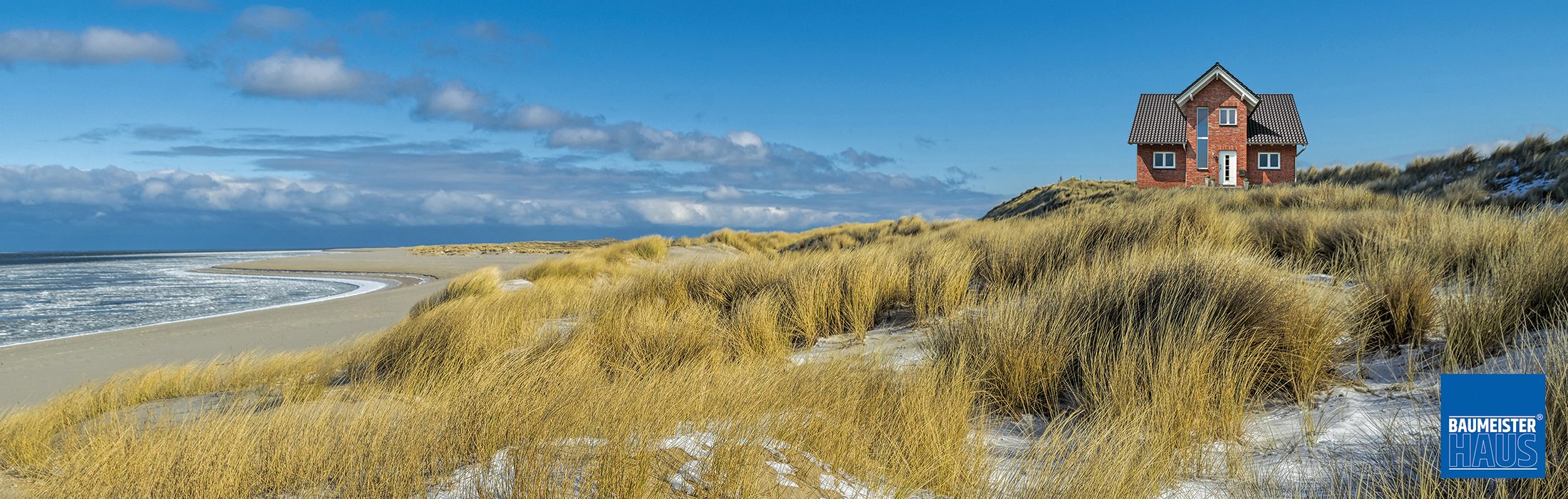 Dünenlandschaft an der ostfriesischen Küste mit einem massiv gebauten Klinkerhaus